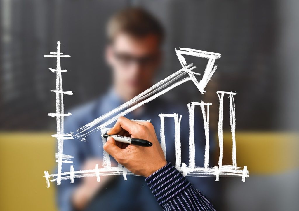 Hand drawing a rising graph on a clear screen, symbolising business growth and success.